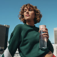 Person holding a BRITA water filter bottle Model Vital with a cityscape in the background