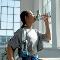 Woman drinking from BRITA water filter bottle Model Vital in gym