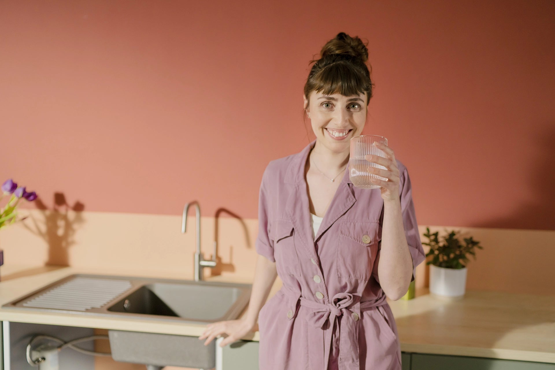 Smiling woman drinking in kitchen