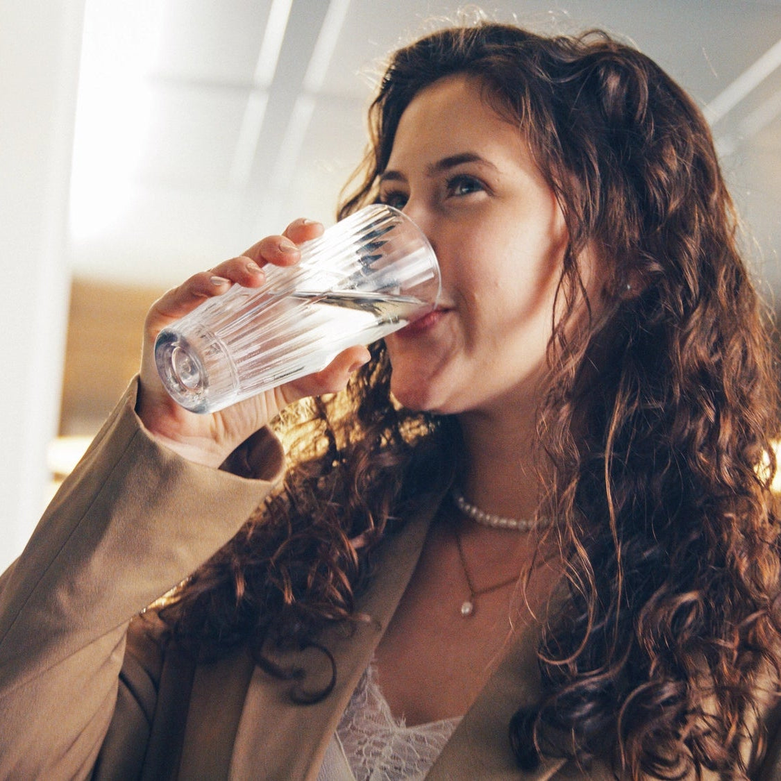 Woman drinking water indoors with blurred background