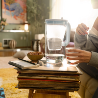 Woman sitting on a couch next to a glass jug on a table.