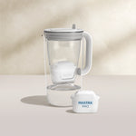 A water filter glass jug in grey on a beige background