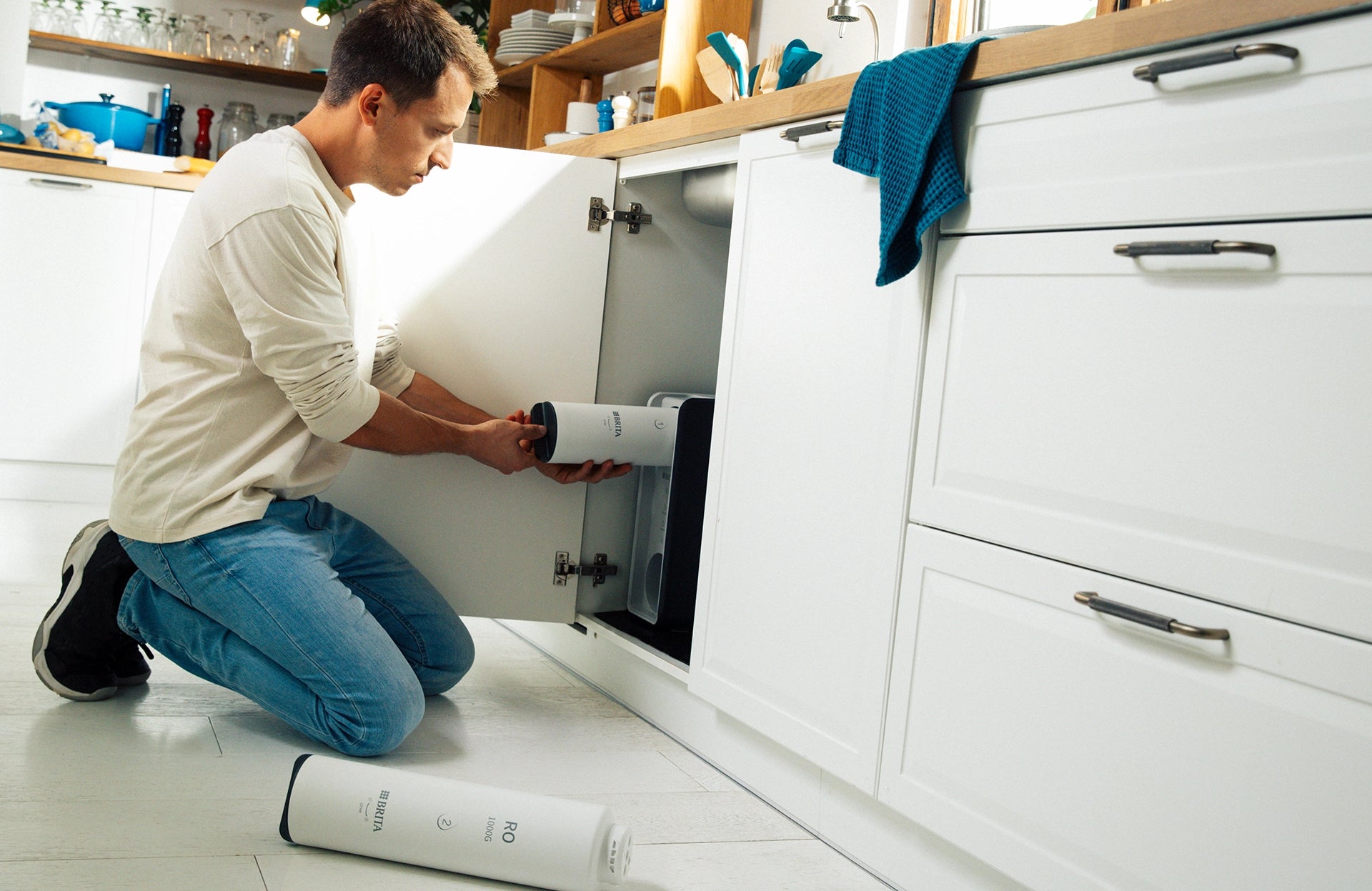 Man inserting BRITA mypure green ro filter under sink