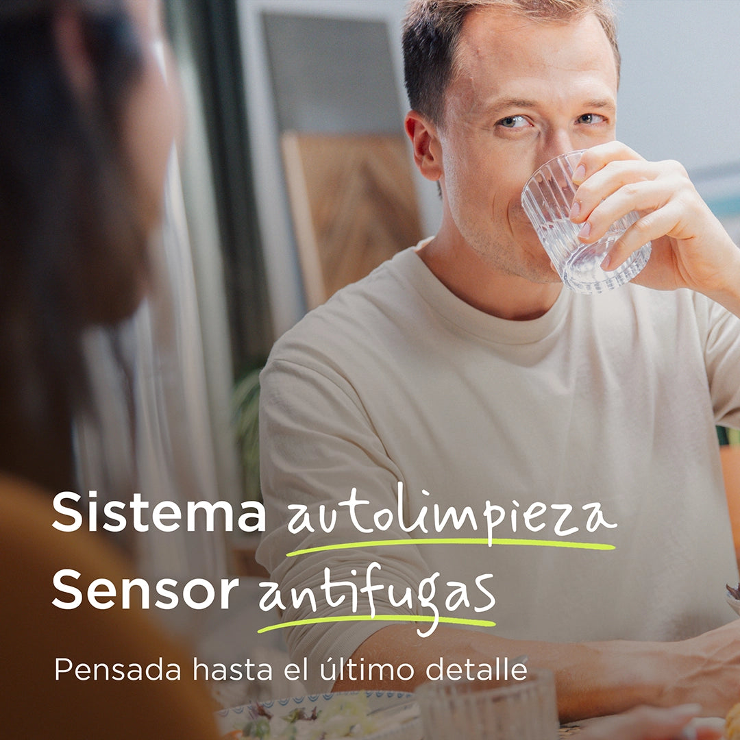 Person drinking a glass of filtered water while sitting at a dining table