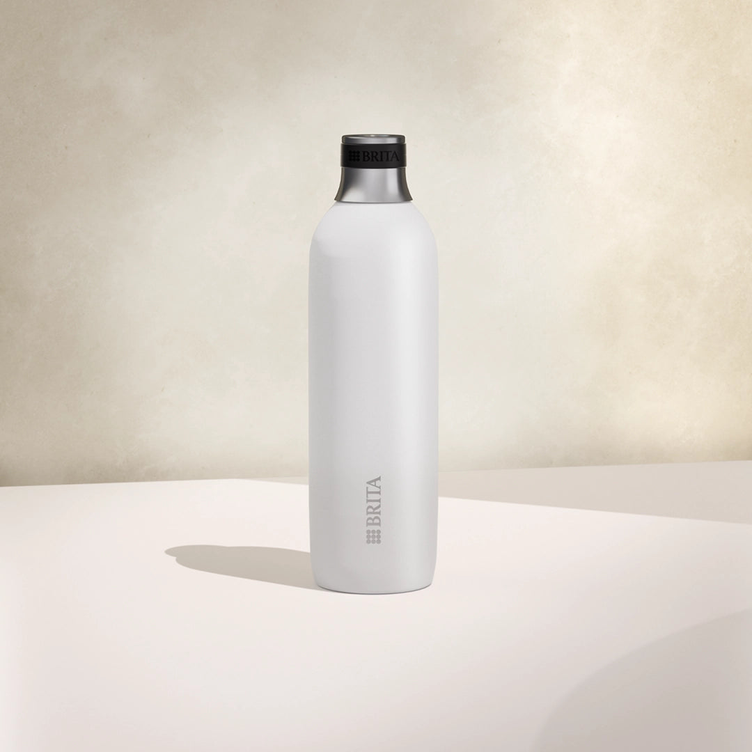 One large white BRITA sodaTRIO stainless steel bottle on a beige background