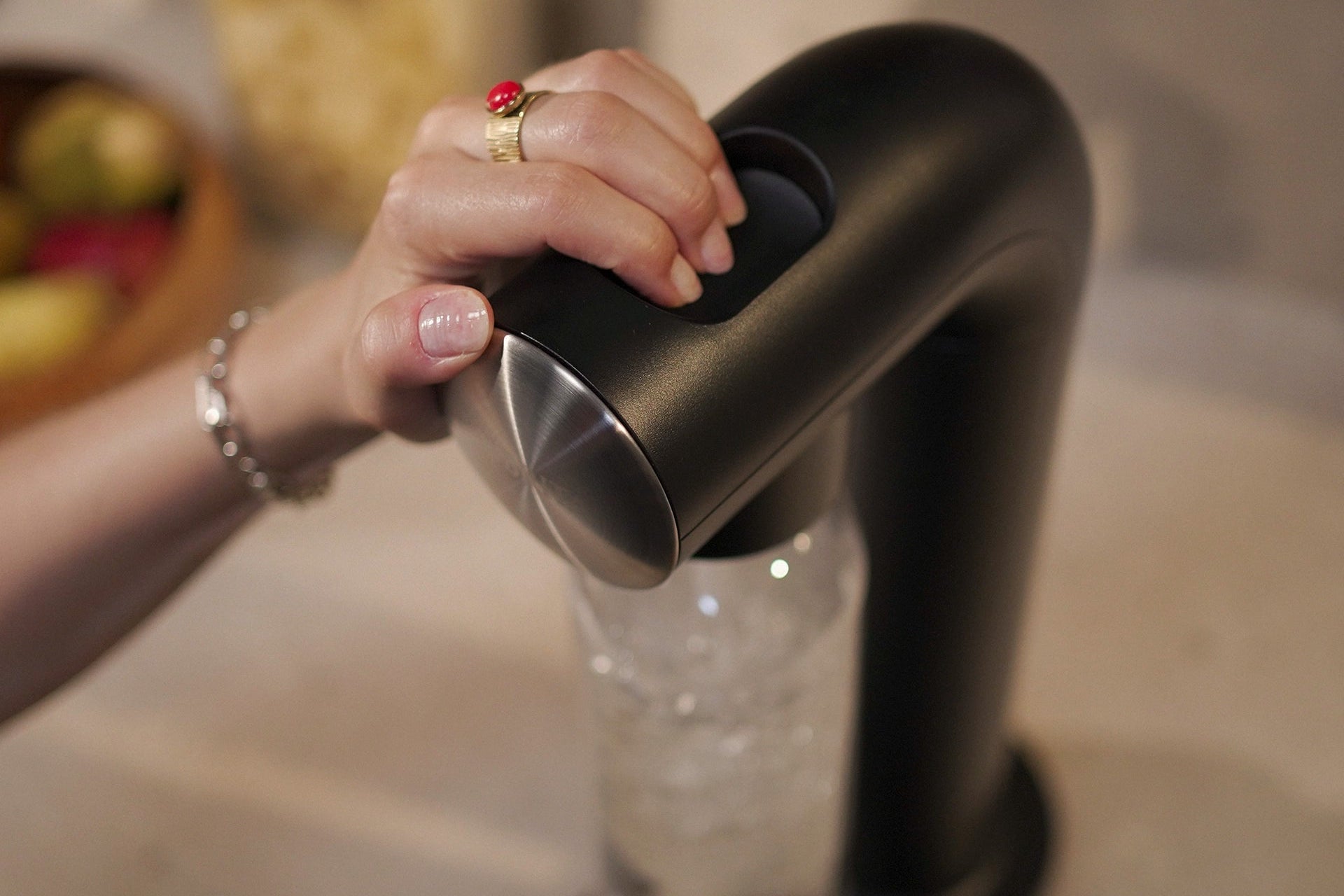 Woman using the BRITA sodaONE Sparkling Water Maker on a kitchen counter.