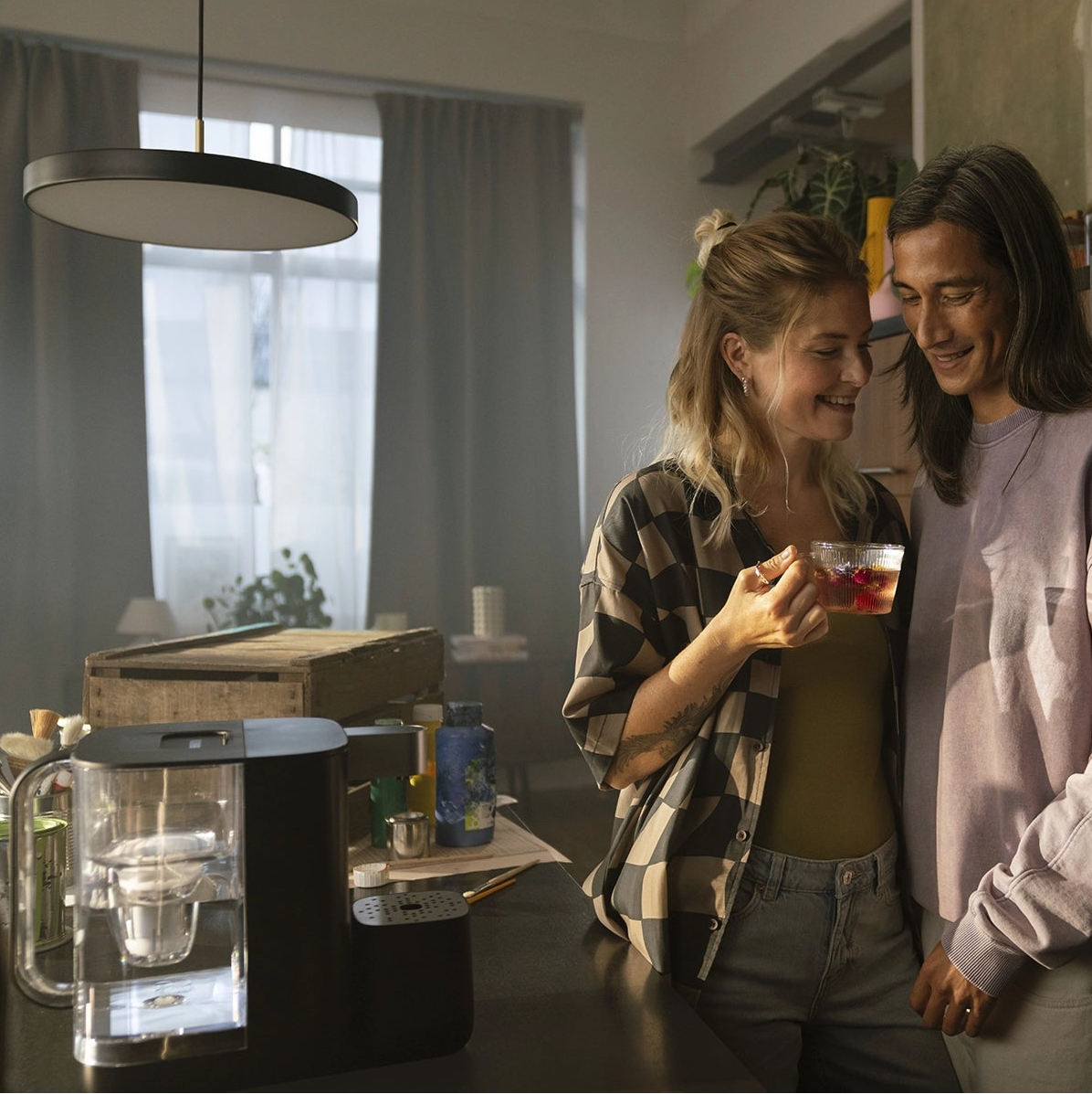 BRITA YOURCE water dispenser on a kitchen counter with two people holding a glass of flavoured water